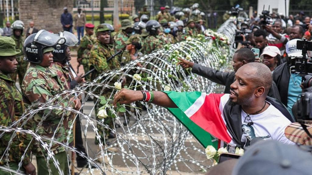 Families lay flowers on barbed wire barricade on anniversary of deadly Kenya protests